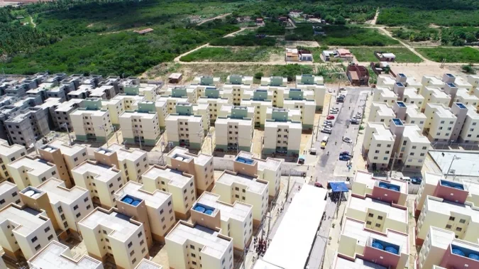 Vista aérea de um conjunto de moradias populares entregues, com prédios novos e ruas abertas