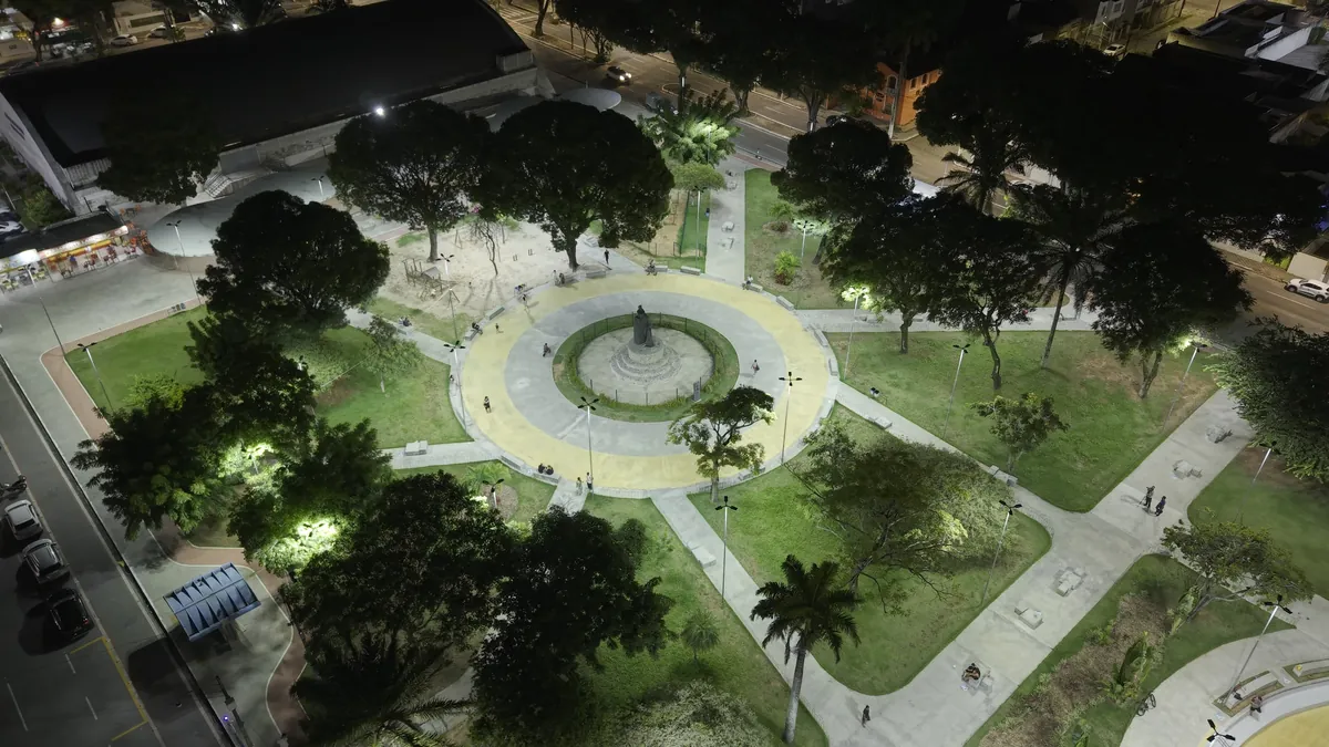 Praça revitalizada e iluminada à noite, com fonte e caminhos novos