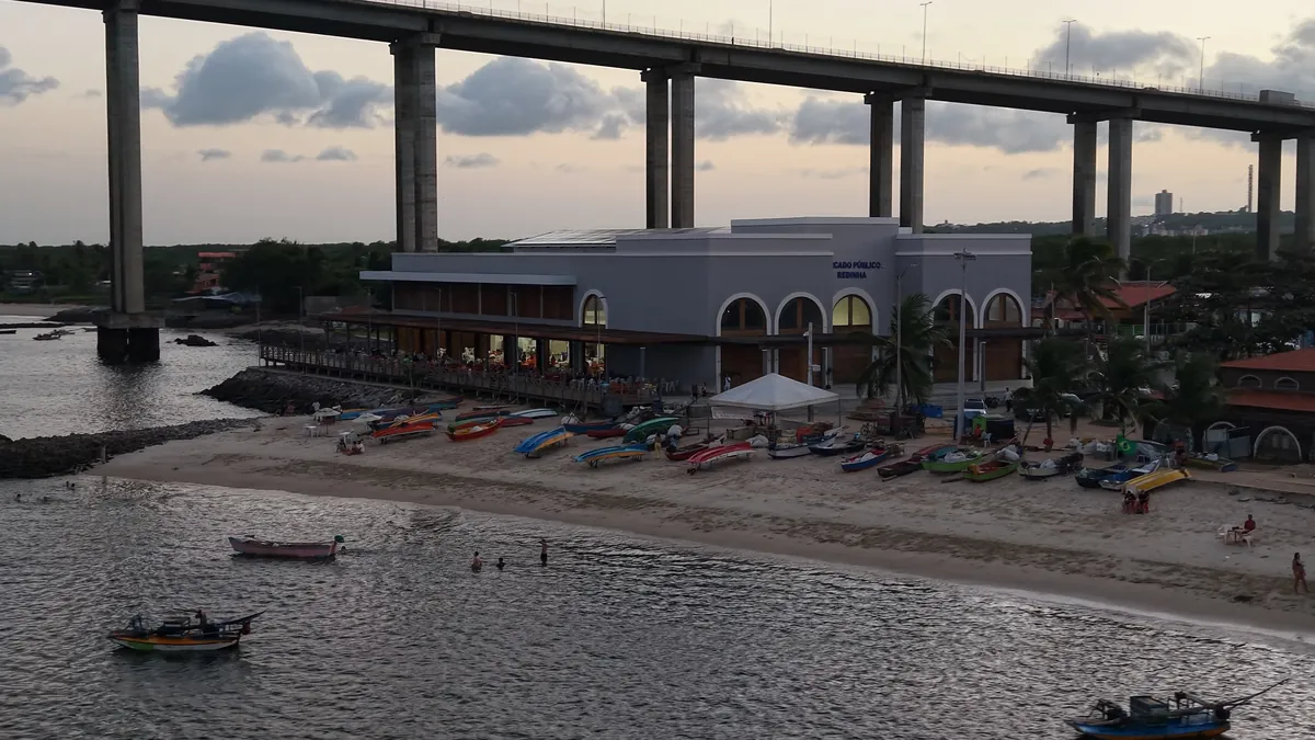 Novo mercado público da Redinha visto da praia, com barcos de pesca e a ponte Newton Navarro por cima